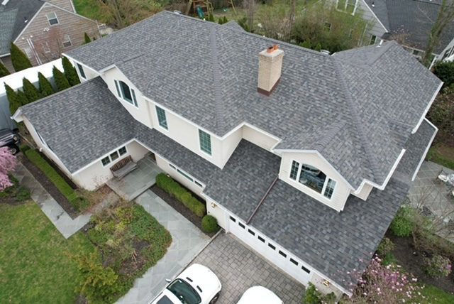 Aerial view of a new gray roof on a white colonial