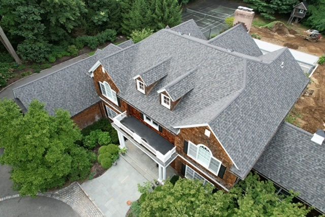Aerial view of a gray roof with dormers among trees