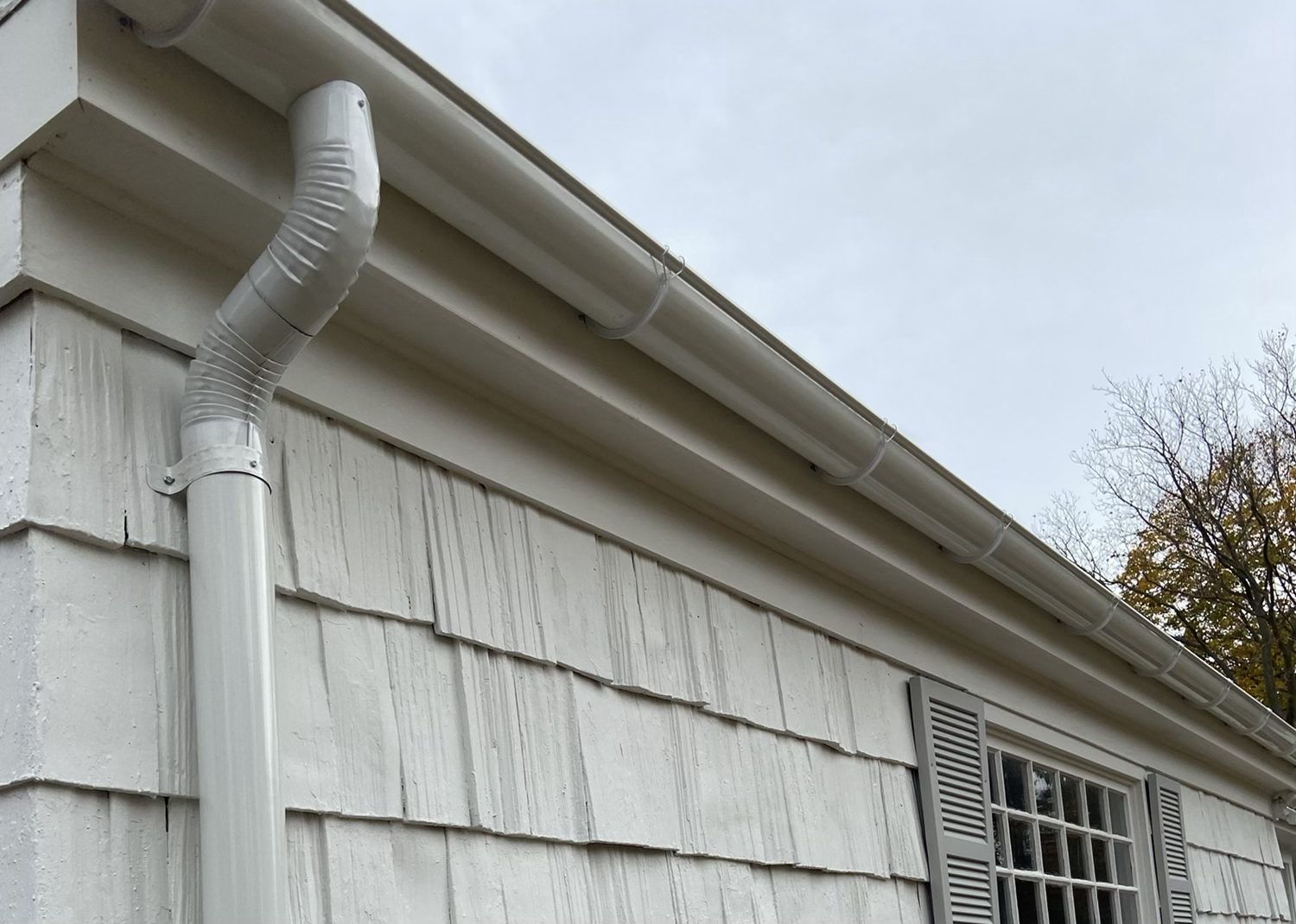 White gutter and downspout on a shingled home